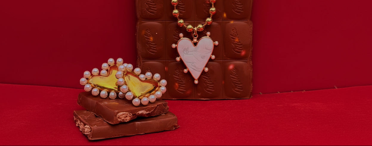 Chocolate bar with a heart-shaped pendant and necklace on stacked chocolate bars on the red background